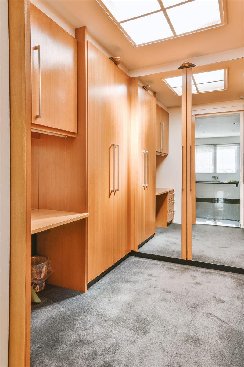 Inloopdressing met houten kastenwand, hoge deuren en een spiegeldeur