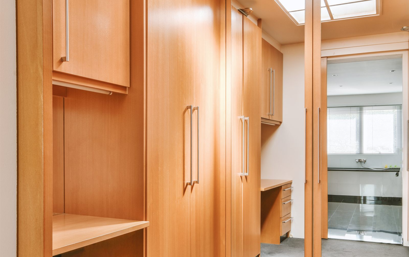 Inloopdressing met houten kastenwand, hoge deuren en een spiegeldeur