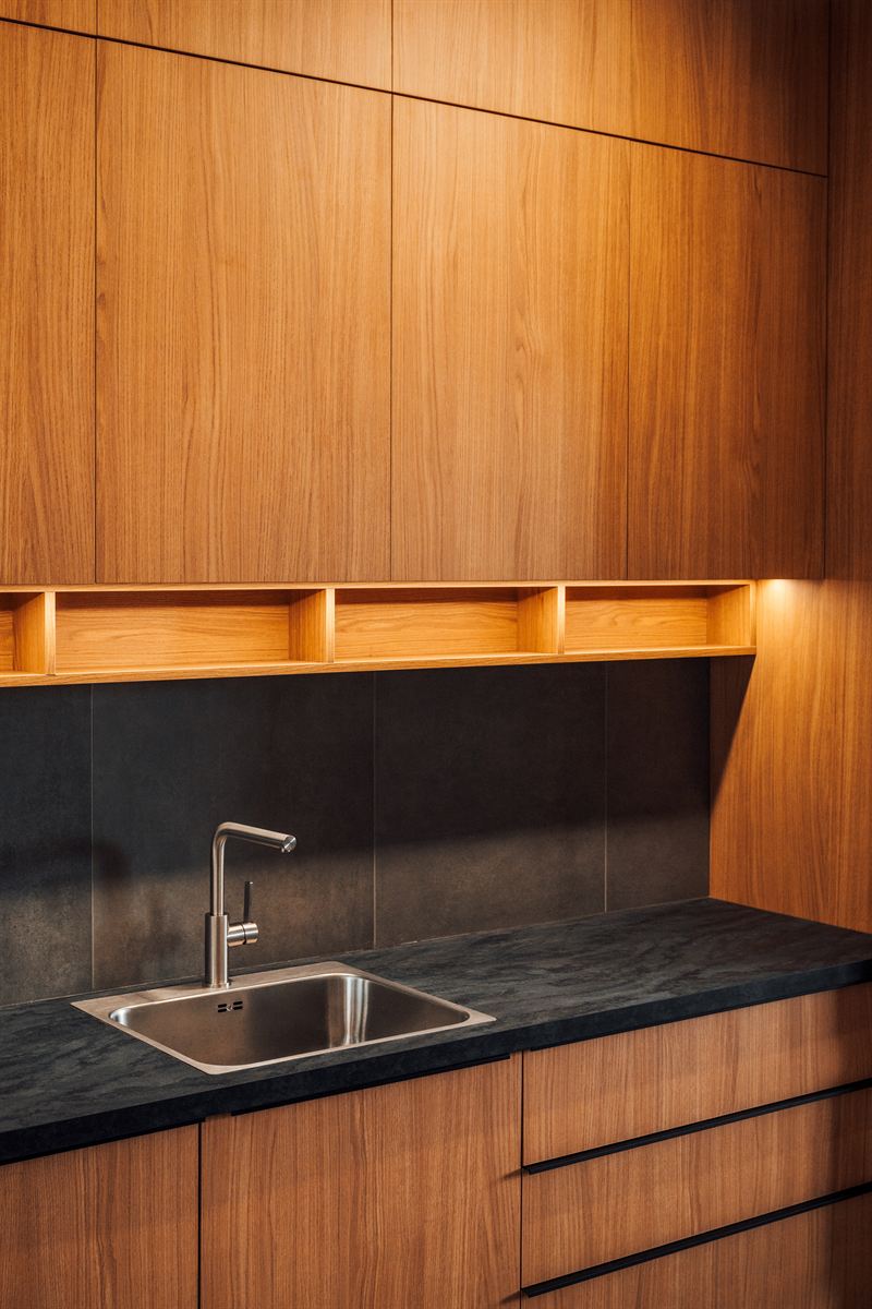 Houten keukenwand met een open nis, ledverlichting en een donker werkblad